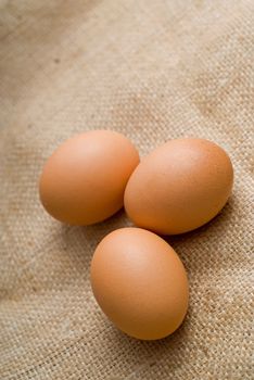 Three farm breakfast eggs on hessian background - portrait orientation