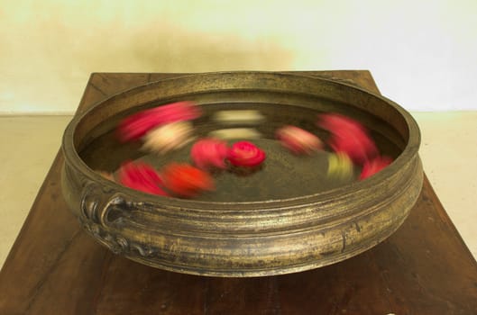 Traditional Indian urli brass bowl with blurred flowers moving rotating inside