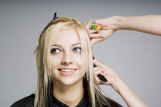 Smiling happy client while hairdresser cutting hair