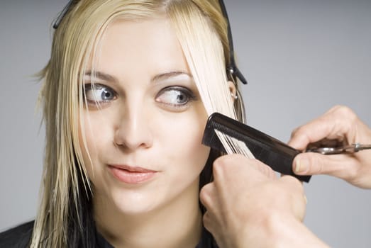 Client looking at comb whie hairdresser cutting hair