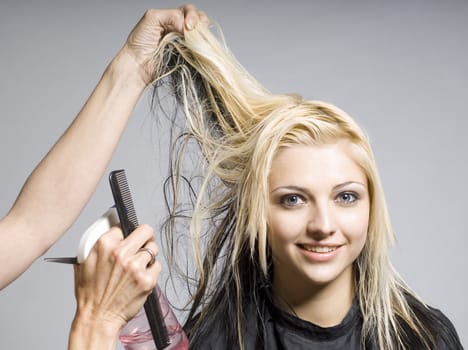 Hairdresser cutting hair of woman of smiling girl