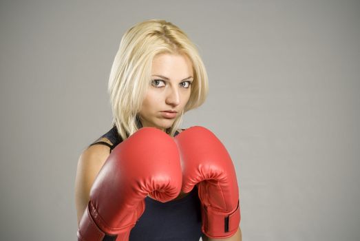 Boxing pose pretty fit blond woman boxer training or working out with red boxing gloves