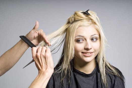 Hairdresser cutting hair of woman of nervous or unsure girl