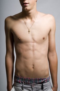 Young man lean stomach muscles with cross or Christian crucifix