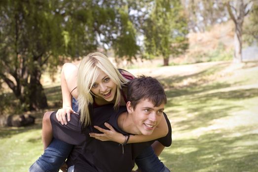 Girl on piggyback of boy friend in park with grass