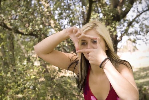 Creative girl or woman photographer framing her photo with finger frame in garden or park