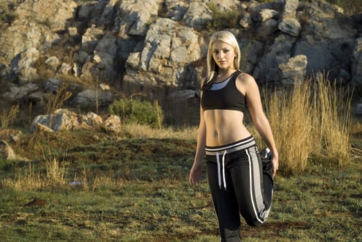 Pretty active woman exercising or stretching warming up in park with golden light reflector