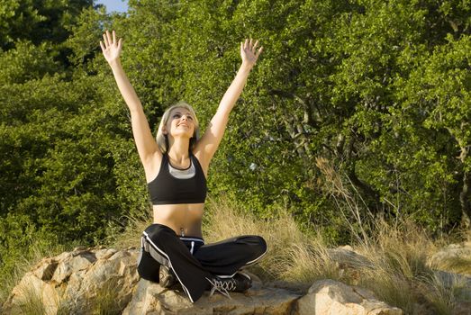 Woman with hands above head in praise in park