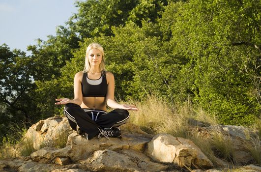 Pretty woman meditating on rock open hands with gold light reflector