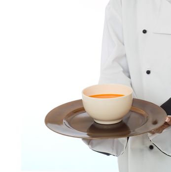 Professional chef in workwear jacket serving soup isoltated on white