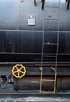 Danger sige and yellow brake wheel on side of toxic chemical railway transport carriage