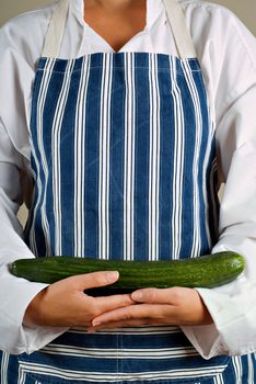 Female woman vegitarian chef or cook holding cucumber vegetable in her hands