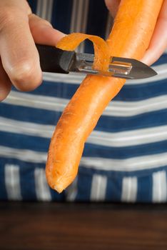 Woman or female cook or chef peeling carrot