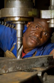 South African or American worker engineer working with industrial drill press