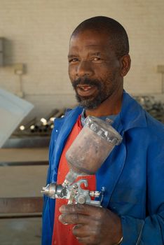 South African or American industrial, worker, handyman painter with spray gun