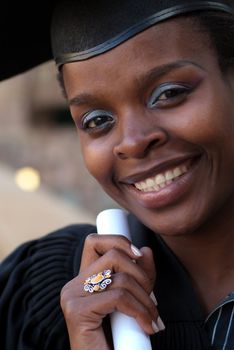 African American college student graduating with mortarboard and diploma or scroll