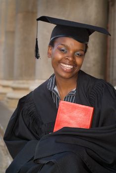 African American college student graduating with mortarboard and book