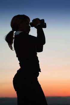 Silhouette of Business Woman with Binoculars Standing on a Hilltop