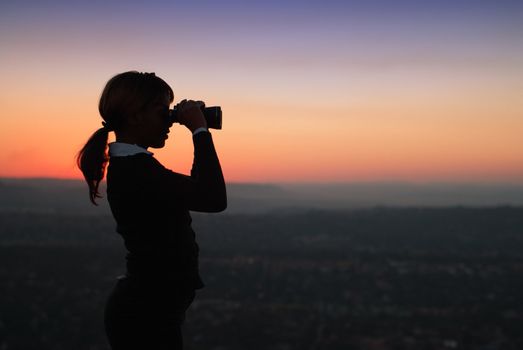 Silhouette of Business Woman with Binoculars Standing on a Hilltop