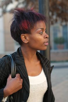 African American businesswoman portrait - looking to the left while waiting for public transport bus at stop