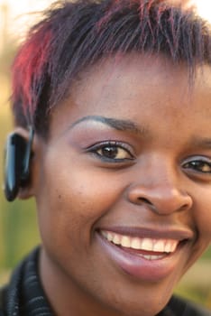 African American businesswoman vertical portrait with bluetooth mobile phone headset - selective focus on left eye