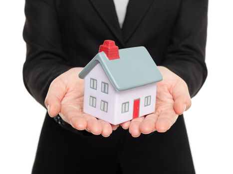 Real estate agent showing mini house / home closeup of female realtor hands showing miniature model house isolated on white background.