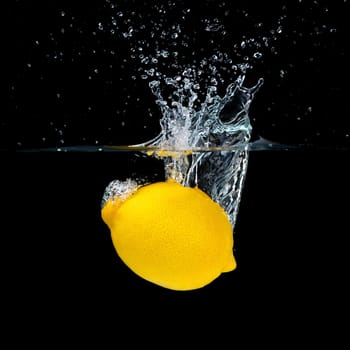 Fresh lemon falling into water. Isolated on black background