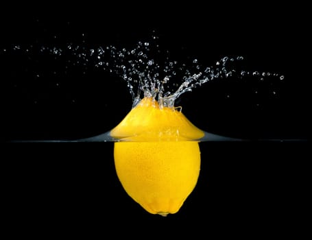 Fresh lemon falling into water. Isolated on black background