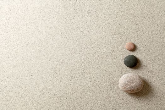 Three colorful zen stones at right side of sand background