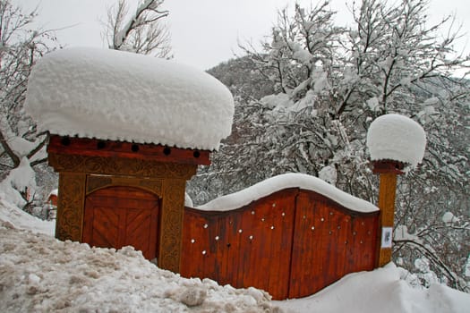 A carved, ornamental wooden gate covered with snow