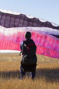 A male paraglider pilot prepares for flight