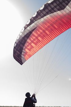 A male paraglider pilot prepares for flight