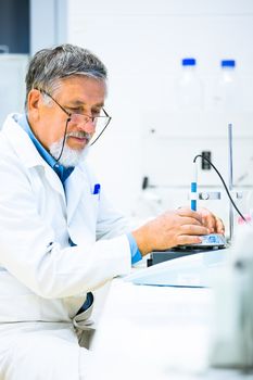 Senior male researcher carrying out scientific research in a lab (shallow DOF; color toned image)