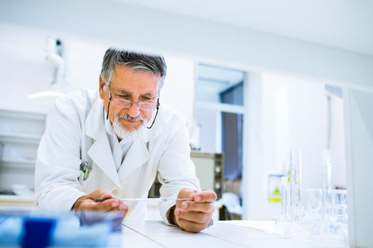 Senior male researcher carrying out scientific research in a lab (shallow DOF; color toned image)