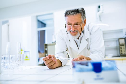 Senior male researcher carrying out scientific research in a lab (shallow DOF; color toned image)