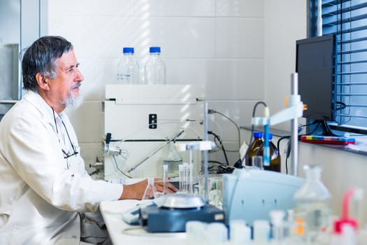 Senior male researcher carrying out scientific research in a lab (shallow DOF; color toned image)