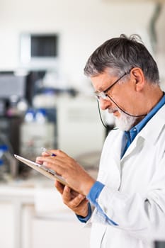 Senior doctor/scientist using his tablet computer at work (color toned image)