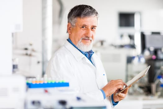 Senior doctor using his tablet computer at work (color toned image)