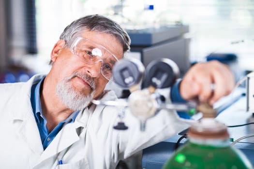 Senior male researcher carrying out scientific research in a lab (shallow DOF; color toned image)