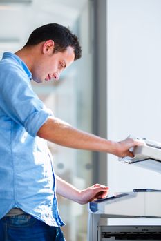 Handsome  young man using a copy machine (shallow DOF; color toned image)