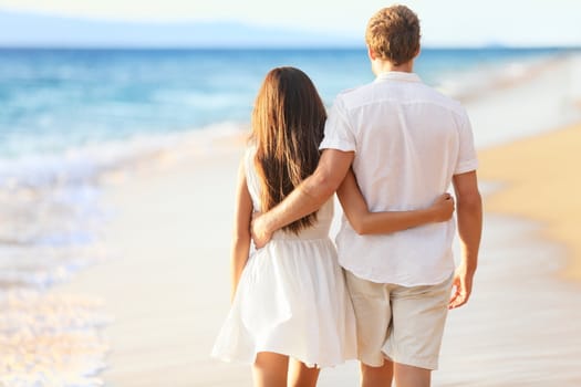 Vacation couple walking on beach together in love holding around each other. Happy interracial young couple, Asian woman and Caucasian man.