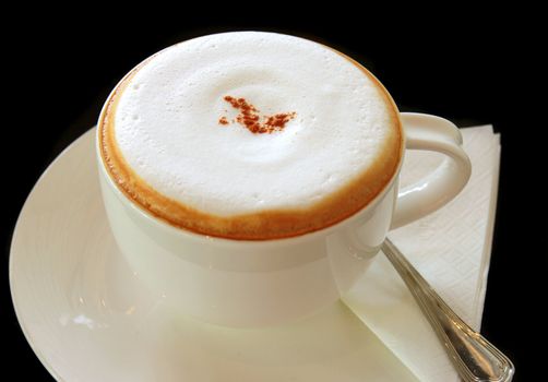 Coffee latte or cappuccino in a cup on black background