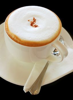 Coffee latte or cappuccino in a cup on black background