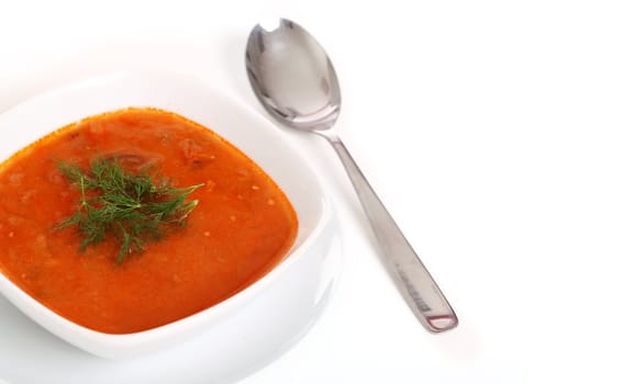 Image of bowl of hot red soup and silver spoon isolated on white background