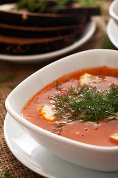 Image of bowls of hot red soup served with bread on a beige tablecloth