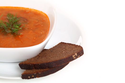 Image of bowl of hot red soup and piece of black bread isolated on white background