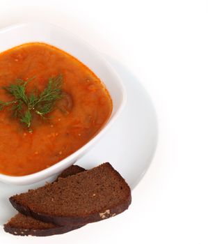 Image of bowl of hot red soup and piece of black bread isolated on white background