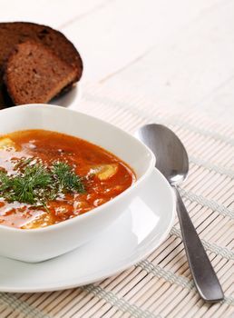 Image of bowl of hot red soup isolated on white wooden table