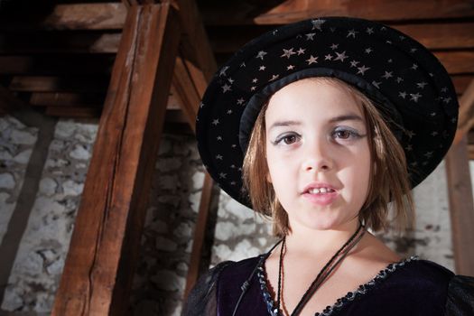 Adorable young female witch wearing cap with stars