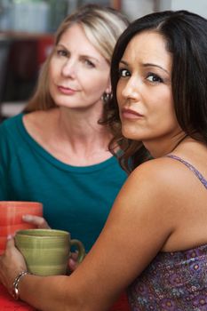 Concerned Hispanic and Caucasian ladies sitting in restaurant